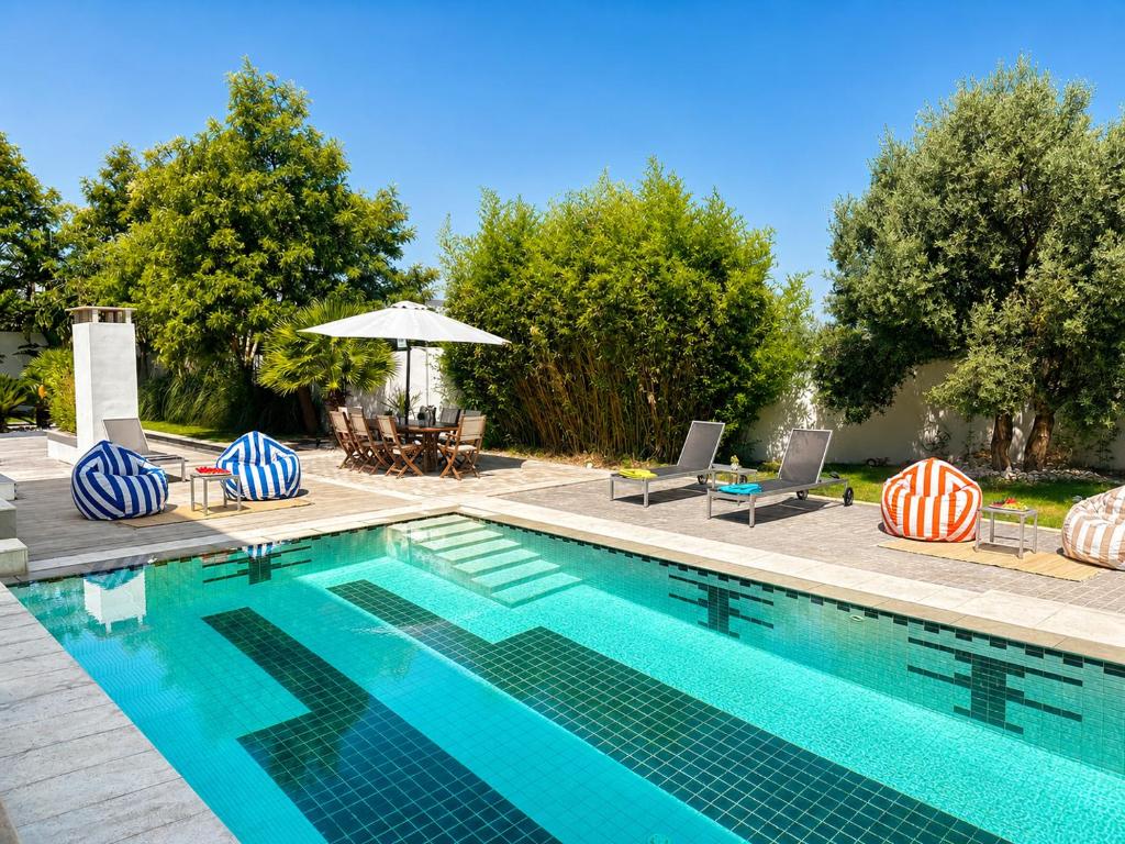 a swimming pool with chairs and an umbrella at Villa Solis Elegant Villa with Private Pool in La Marsa