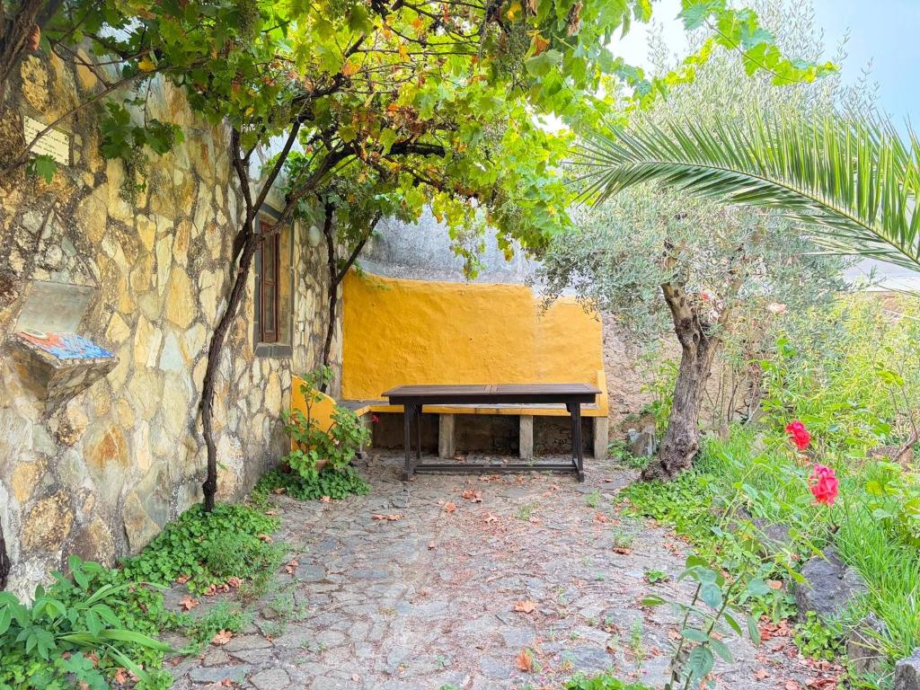 a wooden bench sitting next to a stone wall at Solar Verbena in Vaiamonte
