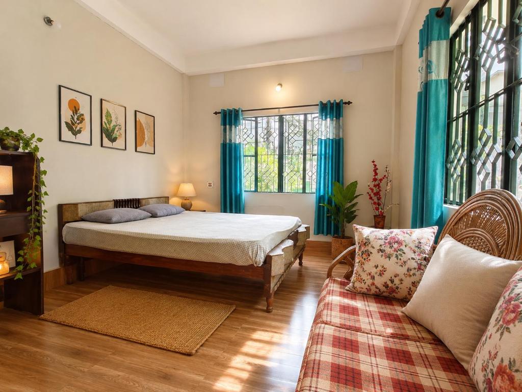 a bedroom with a bed with blue curtains and a couch at Sai Vatika Salbari Stays in Siliguri