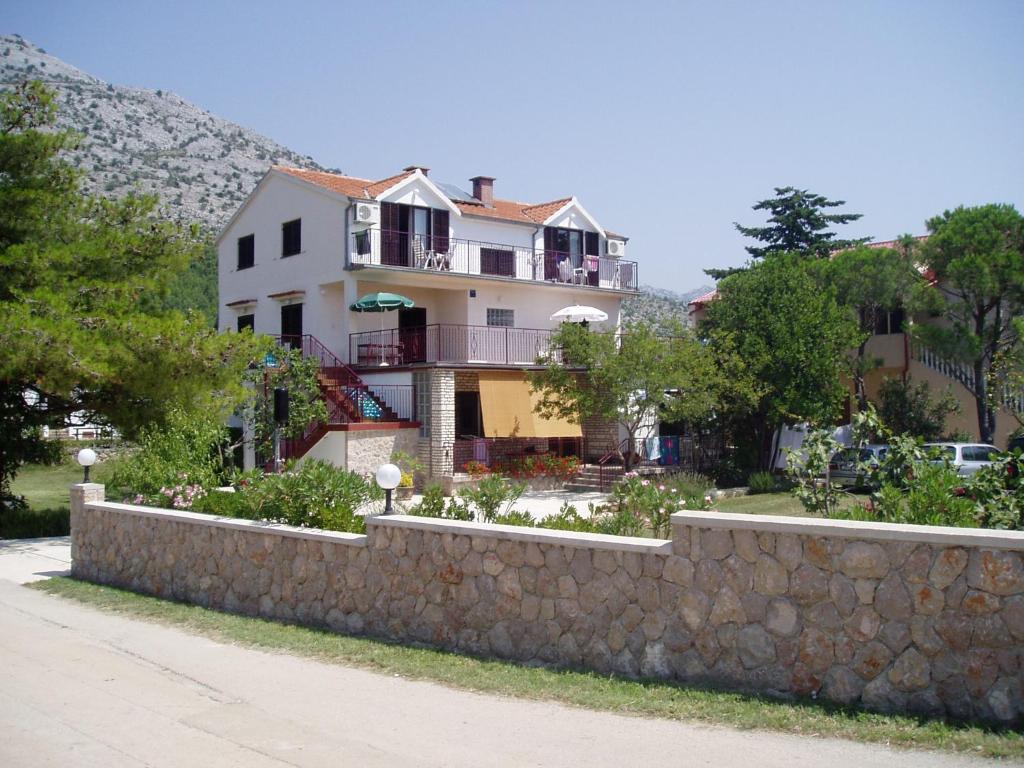 a large house behind a stone wall next to a sidewalk at Apartments & Rooms Luka in Starigrad-Paklenica