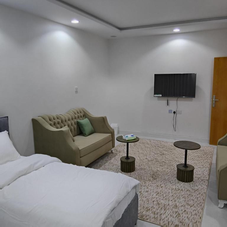a bedroom with a bed and a couch and a tv at شقق غرفتين جديدة واسعة in Musaylah