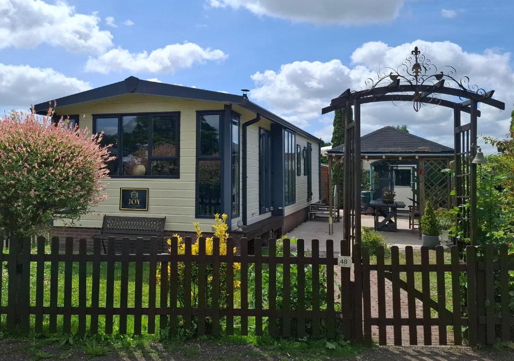 a small house with a fence and a gate at JOY Boutique Chalet Berkhout - Hoorn in De Hulk