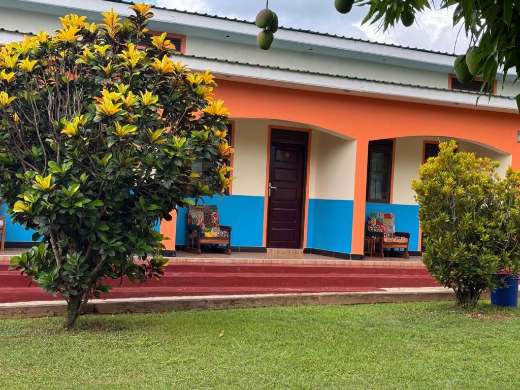 an orange and blue house with a tree at Palm Garden Guest House in Gulu