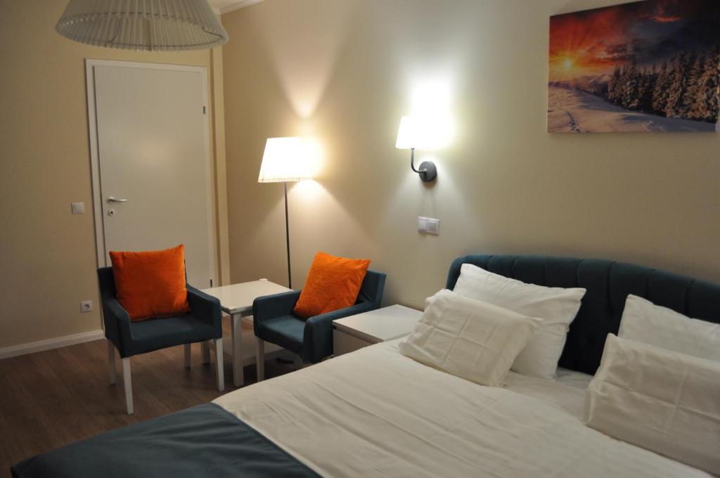 ein Hotelzimmer mit einem Bett und zwei Stühlen in der Unterkunft Transylvania Villa & Spa in Muntele Băişorii