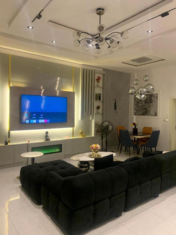 a living room with a black couch and a tv at Polsh residence in Lekki