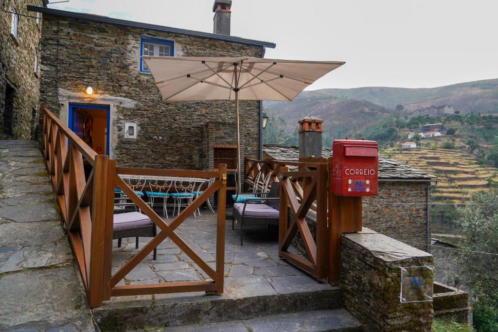 a patio with an umbrella next to a building at Casas Martinho - O Baloiço in Piódão