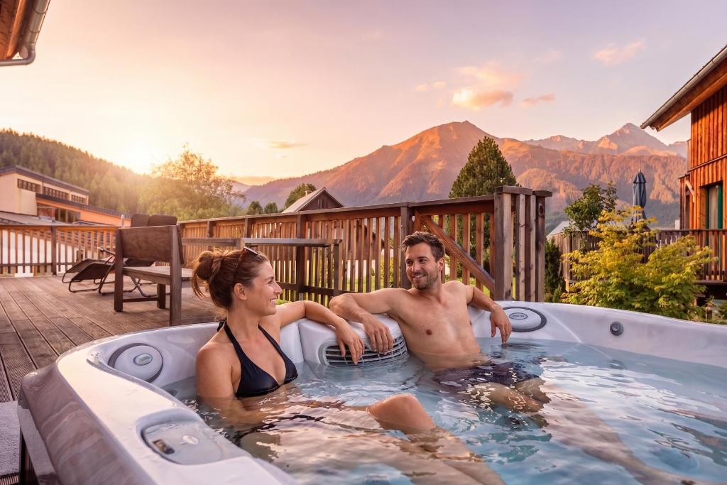 a man and a woman sitting in a hot tub at Almdorf Hohentauern by ALPS RESORTS in Hohentauern