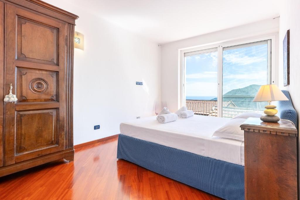a bedroom with a bed and a large window at Hostdomus - Brezza Marina House in Alassio