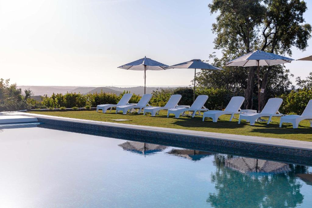 a group of chairs and umbrellas next to a pool at Hotel Rural Quinta do Marco - Nature & Dining in Tavira