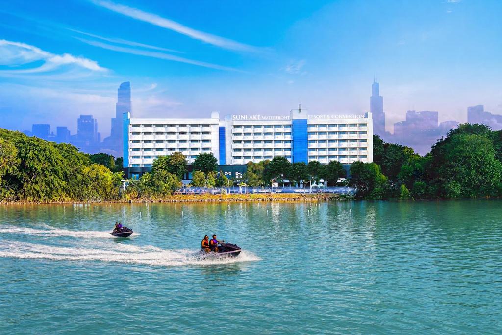 two people on a boat in a lake with a city at Sunlake Waterfront Resort & Convention in Jakarta