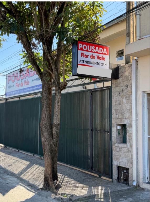 a sign on a building next to a tree at Pousada Flor do Vale in São José dos Campos
