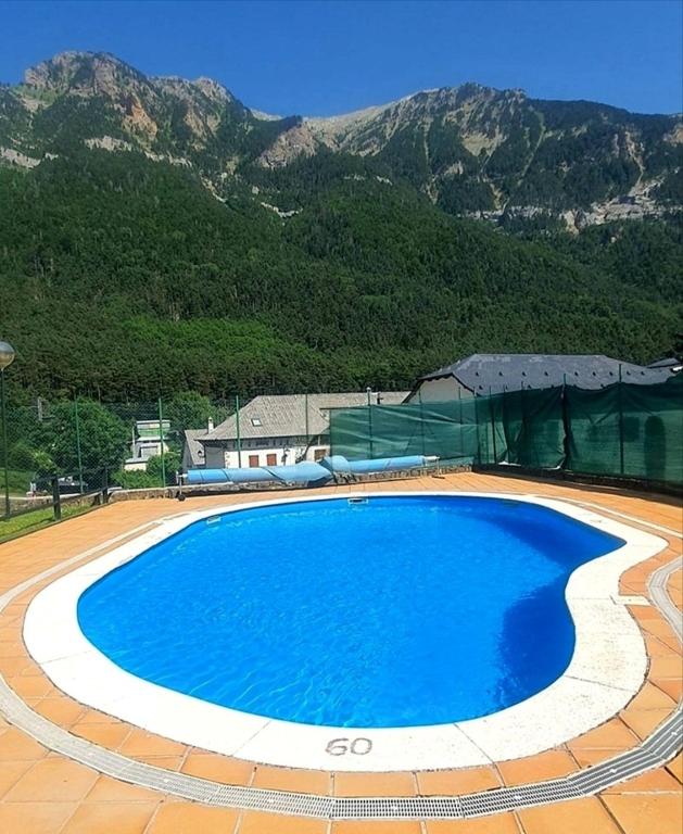 a large blue swimming pool with mountains in the background at Mira Moleta bienvenidos a Canfranc in Canfranc-Estación