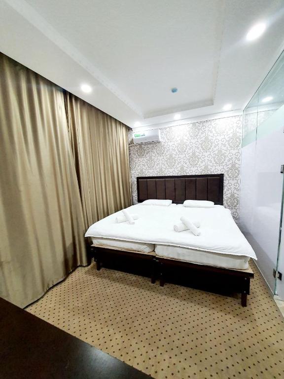 a bedroom with a large bed with white sheets at Alo Grand Hotel in Eshonguzar