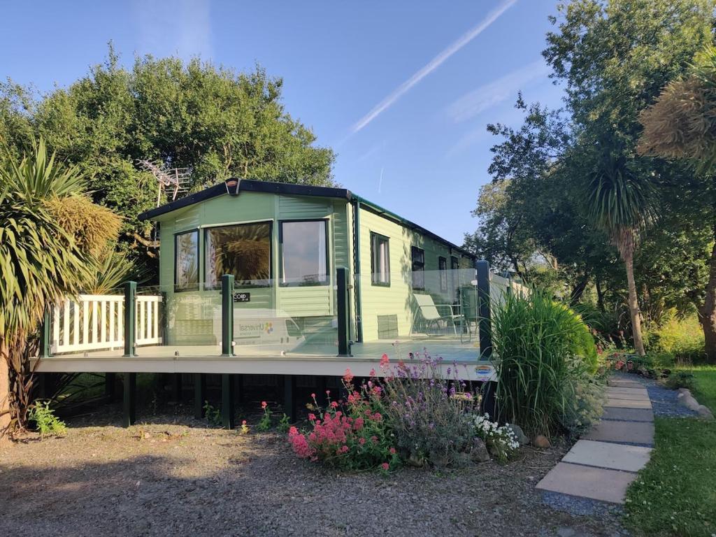 a green tiny house sitting on a trailer at Maggie's Garden Retreat in Millom