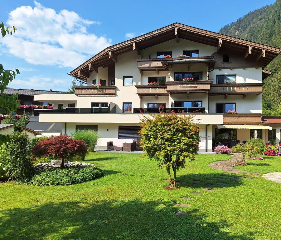 a large apartment building with a green yard at Hotel Garni Erler in Mayrhofen