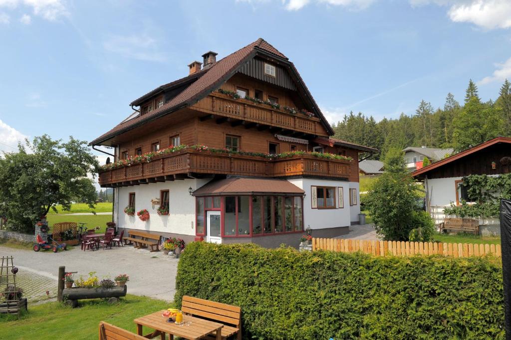 ein großes Holzhaus mit einer Terrasse davor in der Unterkunft Pension Waldesruh/Halseralm in Schladming