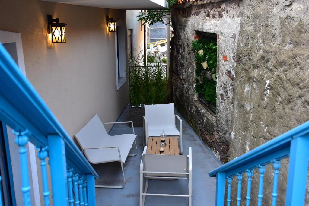 a balcony with white chairs and a table and a wall at Samothrakis Michelangelo 401 in Samothraki