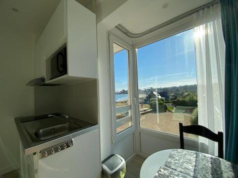 a kitchen with a large window with a view of the ocean at Studio piscine et vue mer in Trévou-Tréguignec