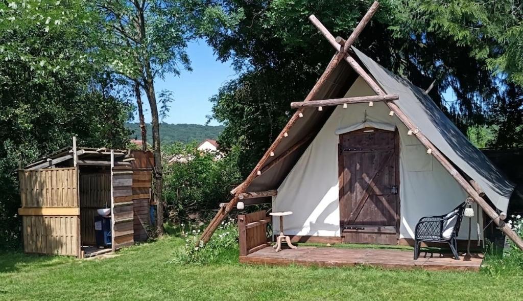 a white tent with a wooden door in a field at Le CLOS SUZANNE in Vesaignes-sous-Lafauche