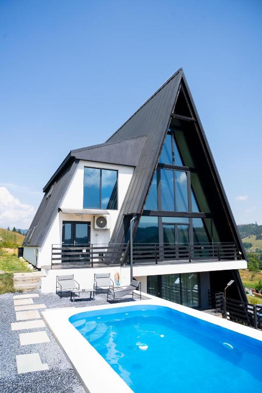 a house with a thatched roof and a swimming pool at Vicanto A frame Bucovina in Gura Humorului