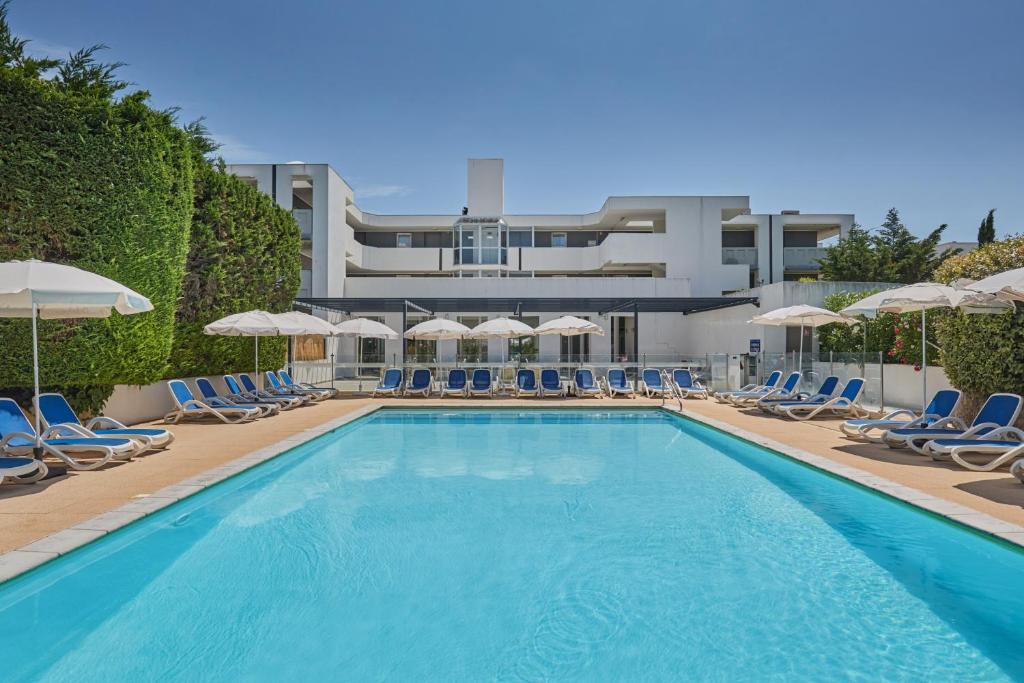 a large swimming pool with chairs and umbrellas at Résidence Odalys Aqualia in Balaruc-les-Bains
