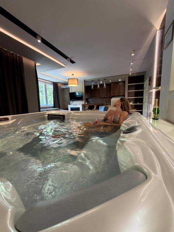 a man laying in a bath tub in a bathroom at Spa Pleasure Apartman in Novi Sad