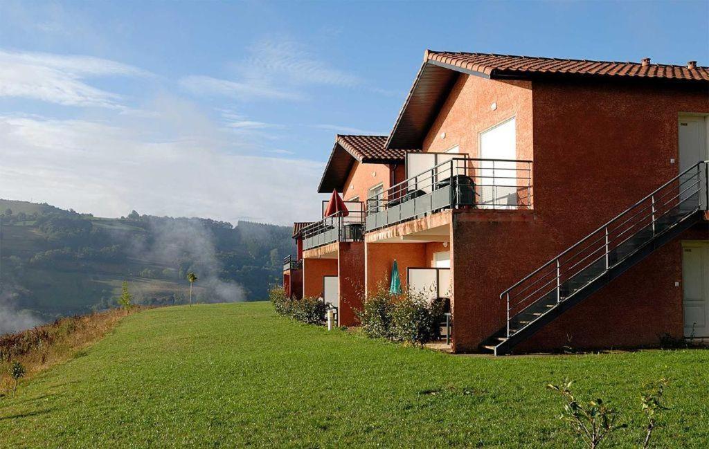 a red brick building on a hill with a green field at Les Abeilles in Trébas