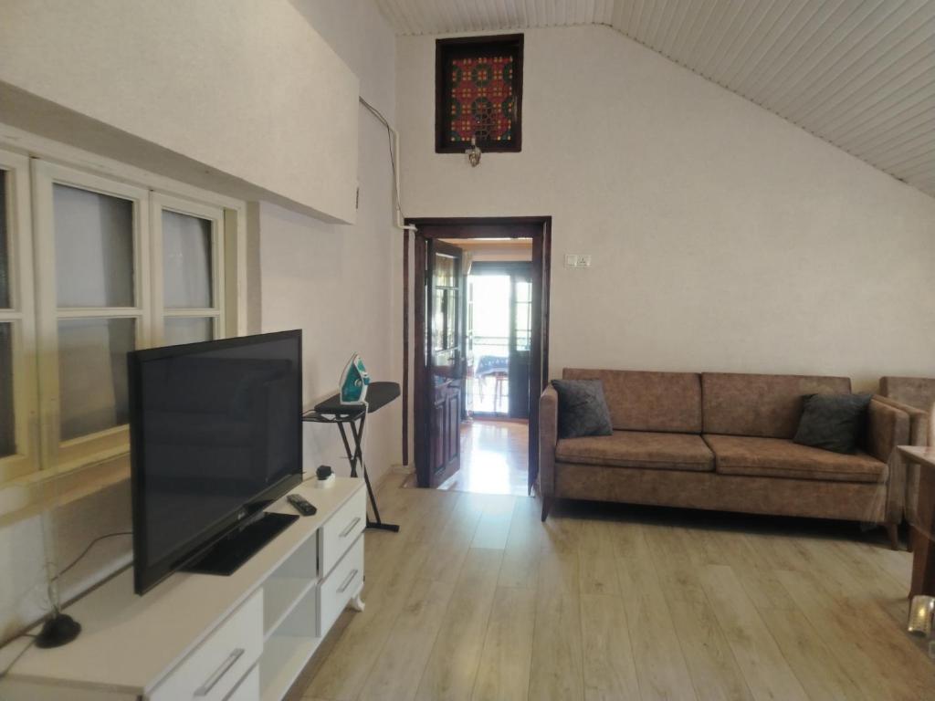 a living room with a flat screen tv and a couch at Mahmud Guest House in Sheki