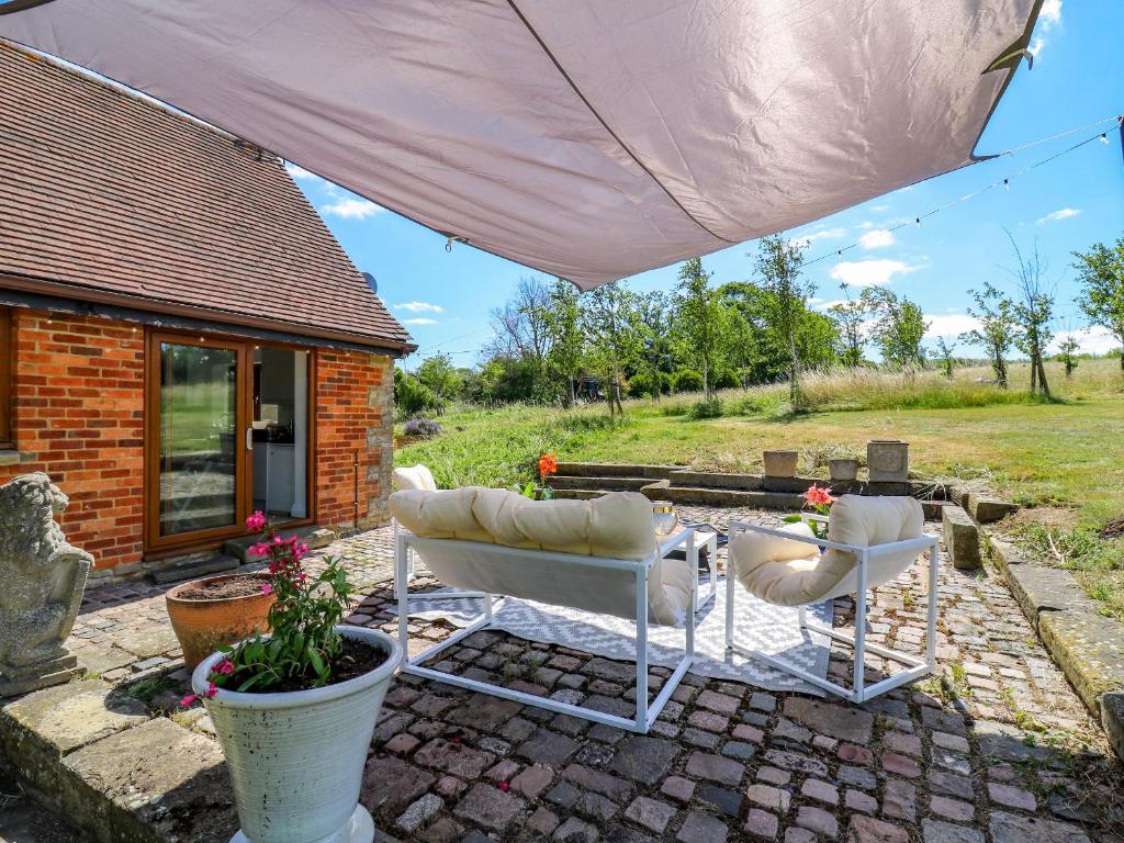 a patio with two chairs and a table under a tent at Barn Owl Cottage in Bedford