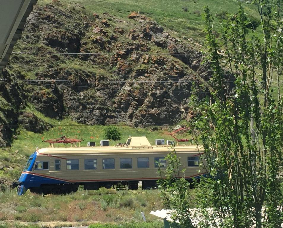 a train parked in a field next to a mountain at Sunrise and Sunset in Lake Sevan in Sevan