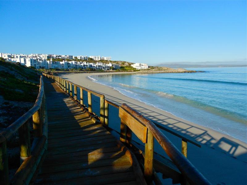 a wooden boardwalk leading to a beach with houses at Malindila Apartment & House in Langebaan
