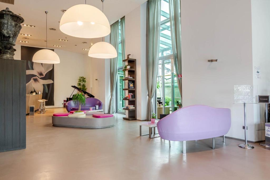 a living room with purple chairs and a purple chair at Hotel For You in Cernusco sul Naviglio