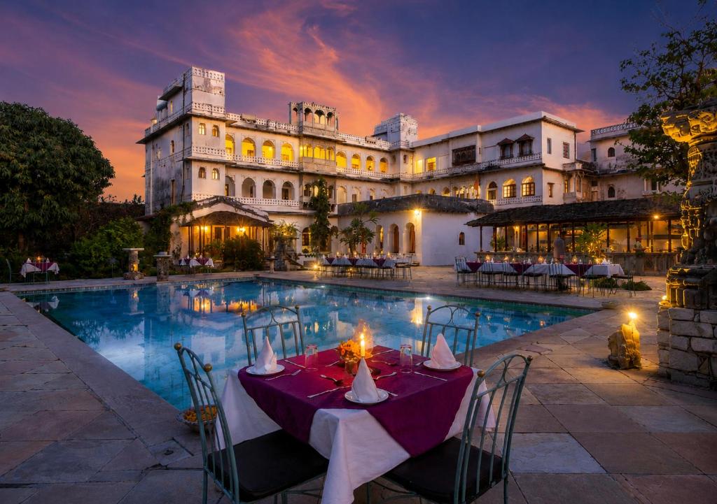 a dining table in front of a building with a pool at Castle Bijaipur - A Luxury Heritage Resort, Chittorgarh in Bijaipur