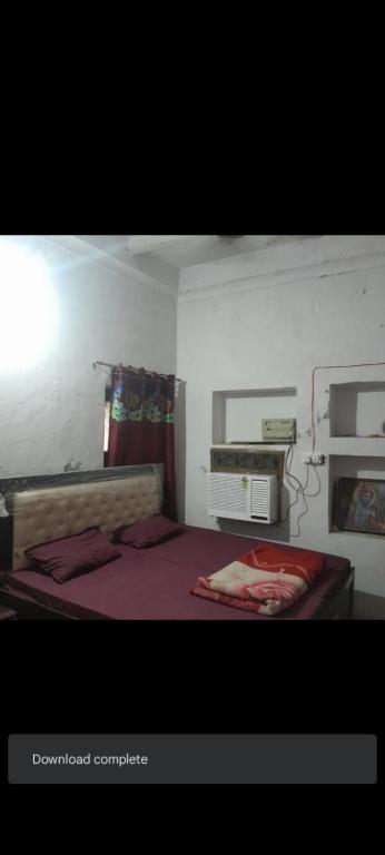 a bedroom with a bed with purple sheets and a window at Sakshi Gopal in Vrindāvan