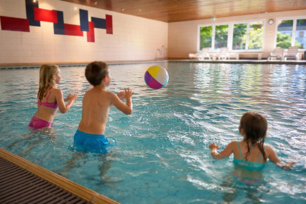 two children playing with a ball in a swimming pool at Familienauszeit Indoorpool, Sauna, optional Vielpass Karte, Netflix, Disney, inkl Bettwäsche Handtücher Reinigung , 100 MBit Internet in Missen-Wilhams