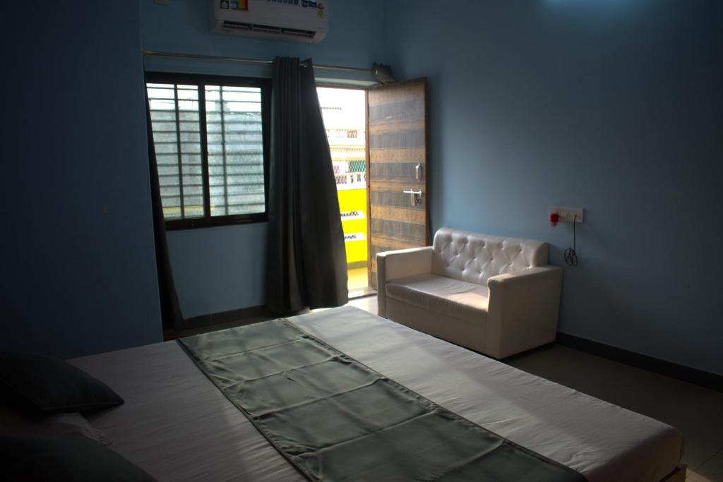 a bedroom with a bed and a chair and a window at Hotel Harsh Garden in Varanasi