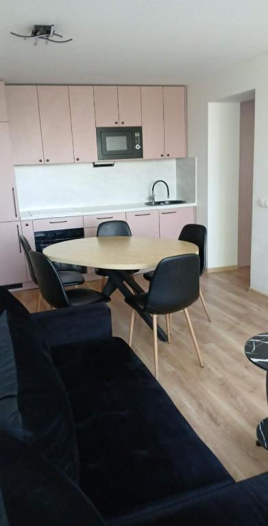 a living room with a table and chairs and a kitchen at Baltas beržas in Anykščiai