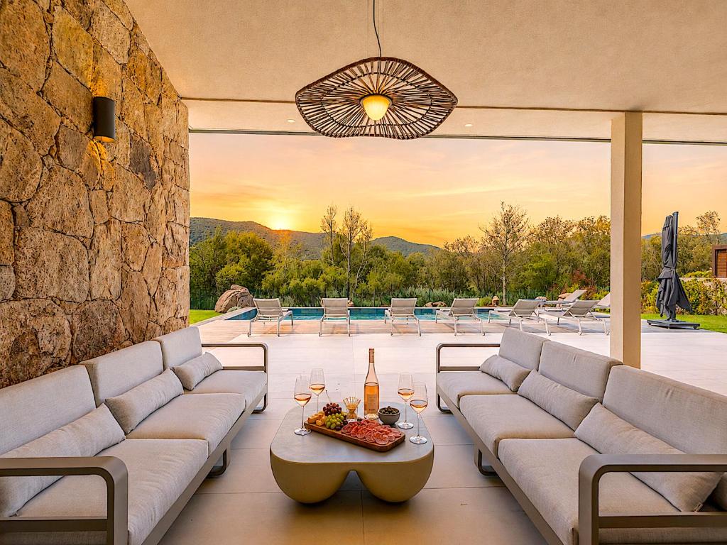 a patio with couches and a table with wine glasses at Villa Déoni in Zonza
