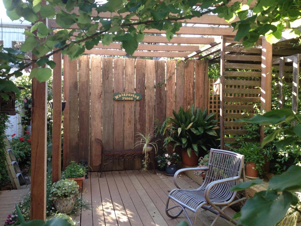 a wooden pergola with a bench and some plants at Whispering Pines Bed and Breakfast in Collie