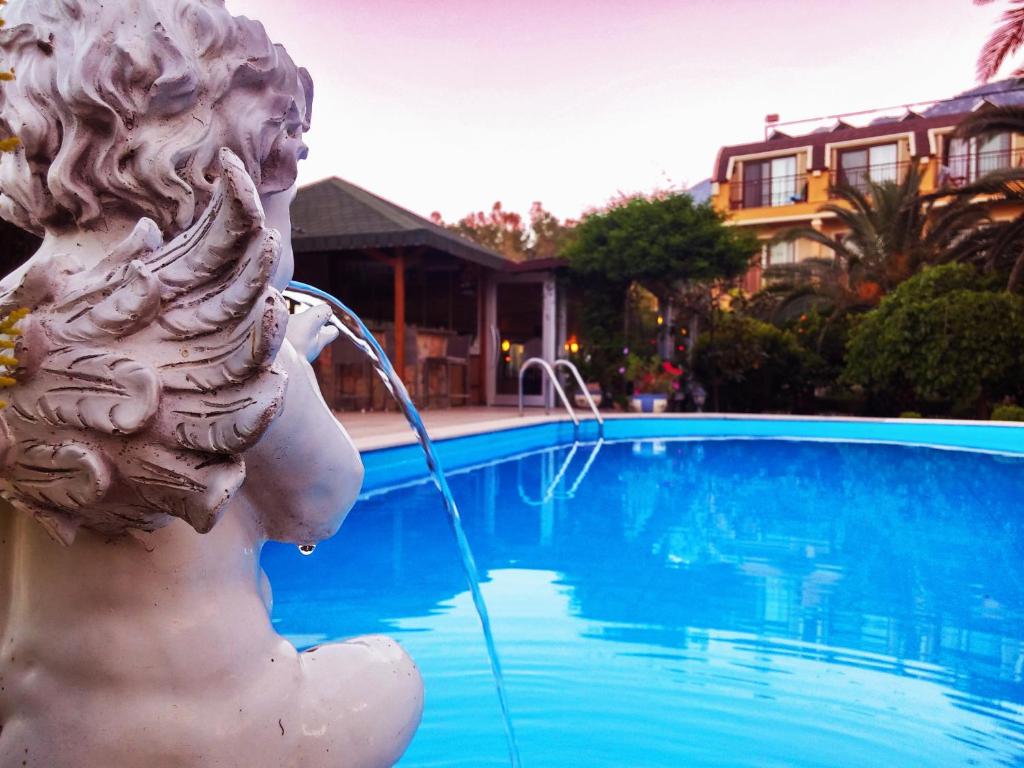 a statue drinking from a water fountain next to a swimming pool at Papirus Hotel in Adrasan