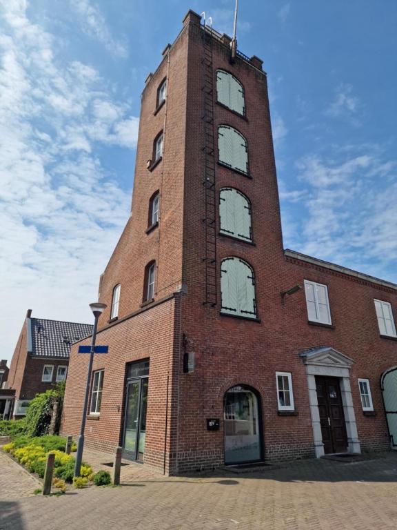 a tall brick building with a clock tower at De Oude Brandweerkazerne 2 tot 4 persoons 2 kamer appartement in Kaatsheuvel