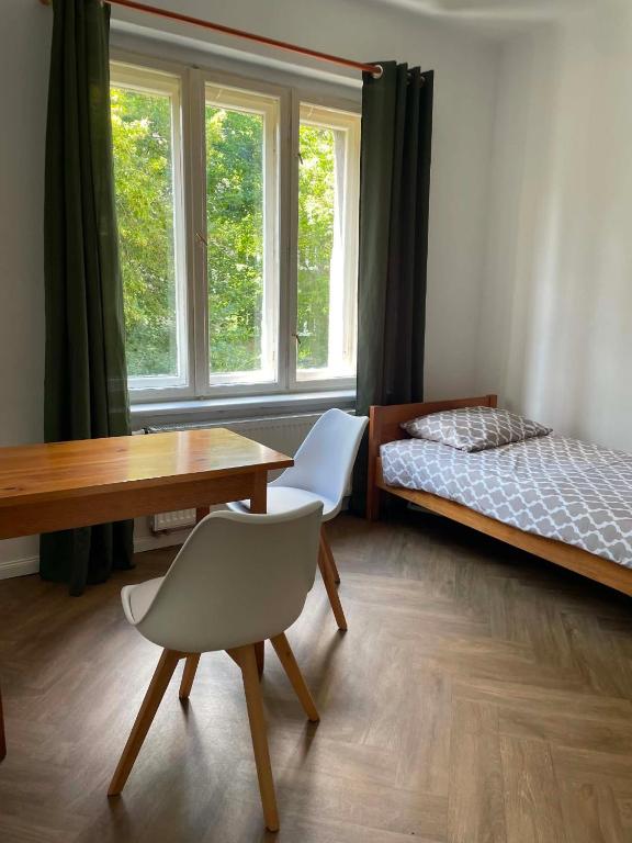a bedroom with a desk and a bed and a table and chairs at HOSTEL Simply Great in Toruń