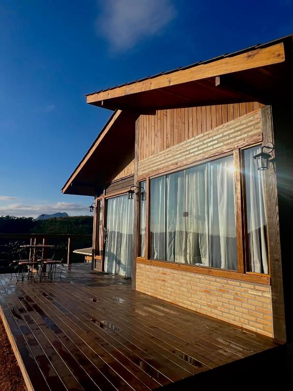 a house with a deck with a table and chairs at Chalé Pazinato in Venda Nova do Imigrante