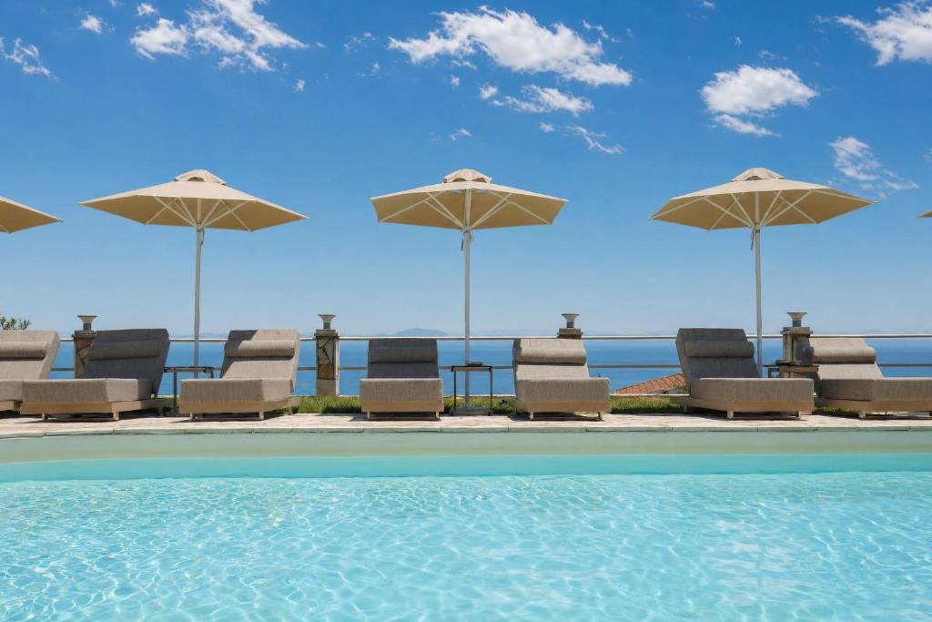 a group of chairs and umbrellas next to a swimming pool at Anasa Corfu in Benitses