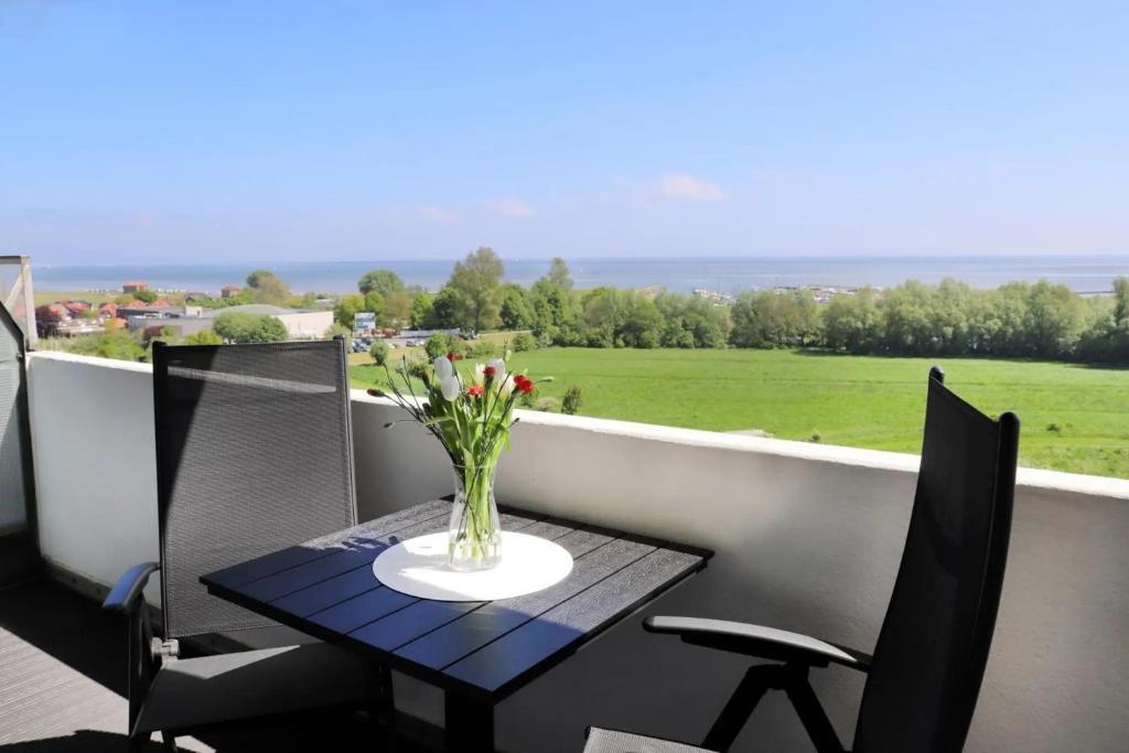 a vase of flowers on a table on a balcony at Meerblick D9 mit Balkon und Pool in Wangerland