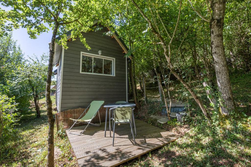 a deck with two chairs and a table in front of a house at Tiny House au coeur de la nature in Bessuéjouls