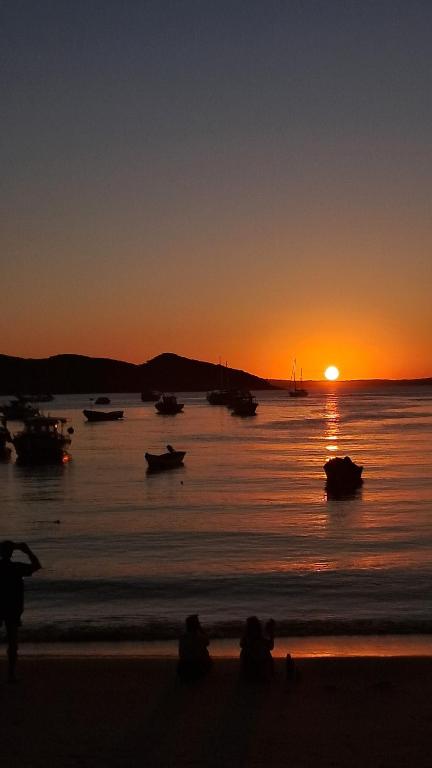 a sunset on a beach with boats in the water at L&S casa da lagoa in Búzios