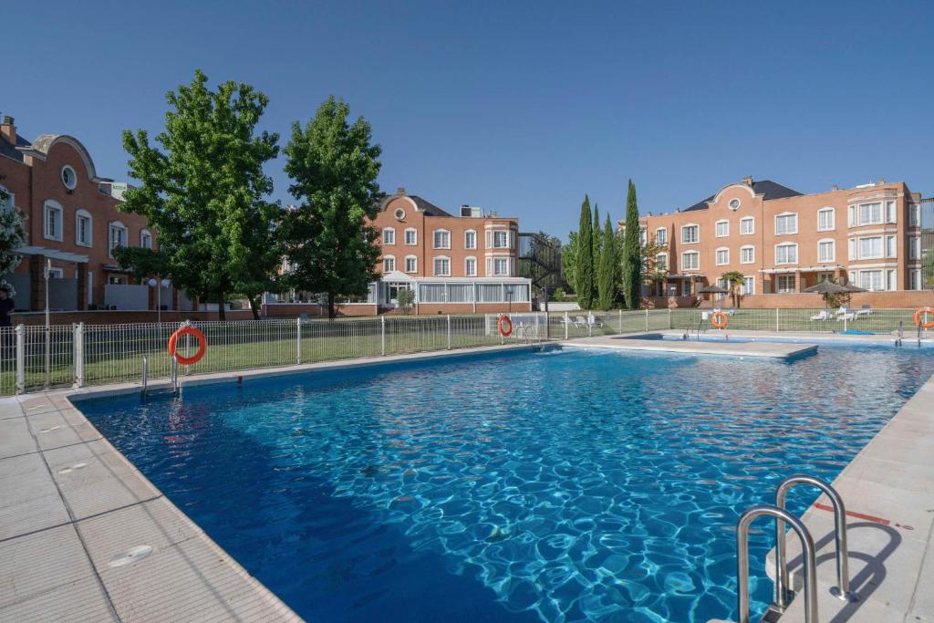 a large pool with blue water in front of buildings at Exe Zarzuela Park in Madrid