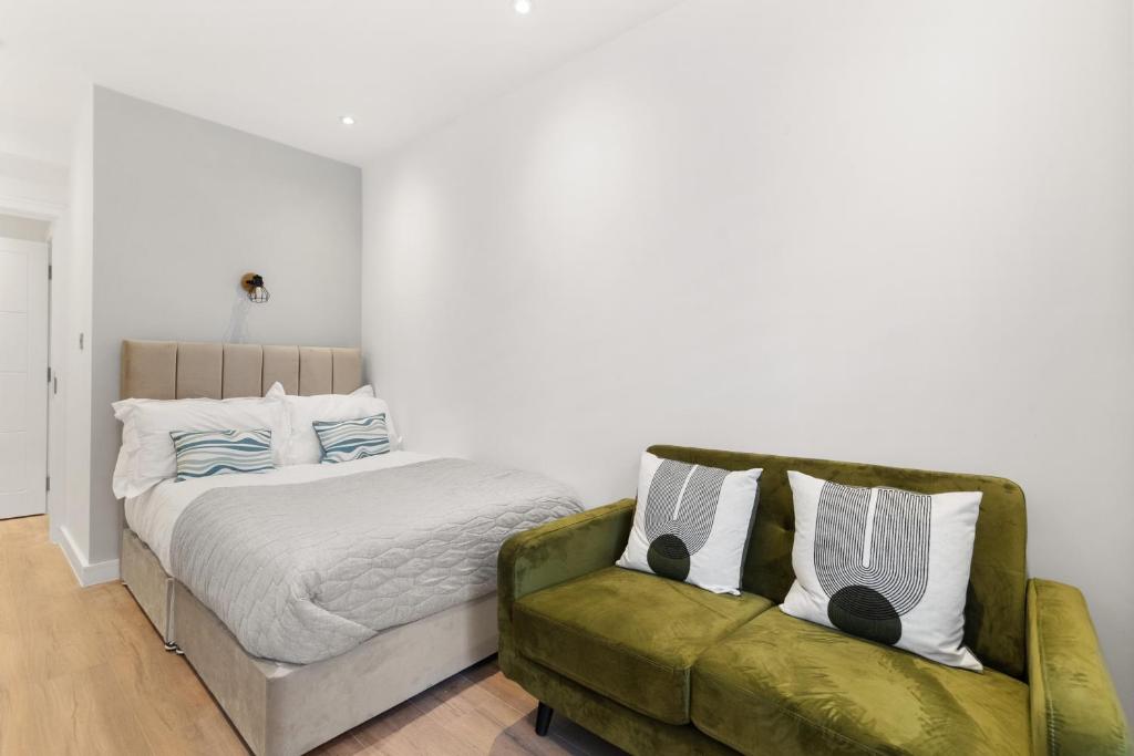 a bedroom with a bed and a green couch at Chic & Modern Beckenham Retreat in Beckenham