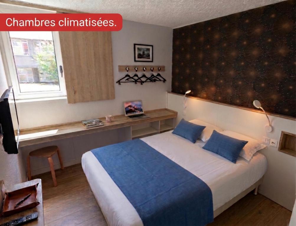 a bedroom with a large bed with blue pillows at Brit Hotel Montpellier Euromédecine in Montpellier